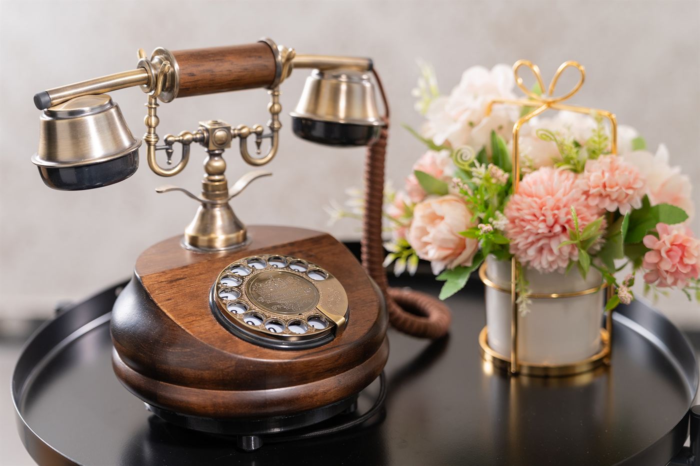 Edles Holztelefon mit Messing-Hörer neben einem Blumengesteck